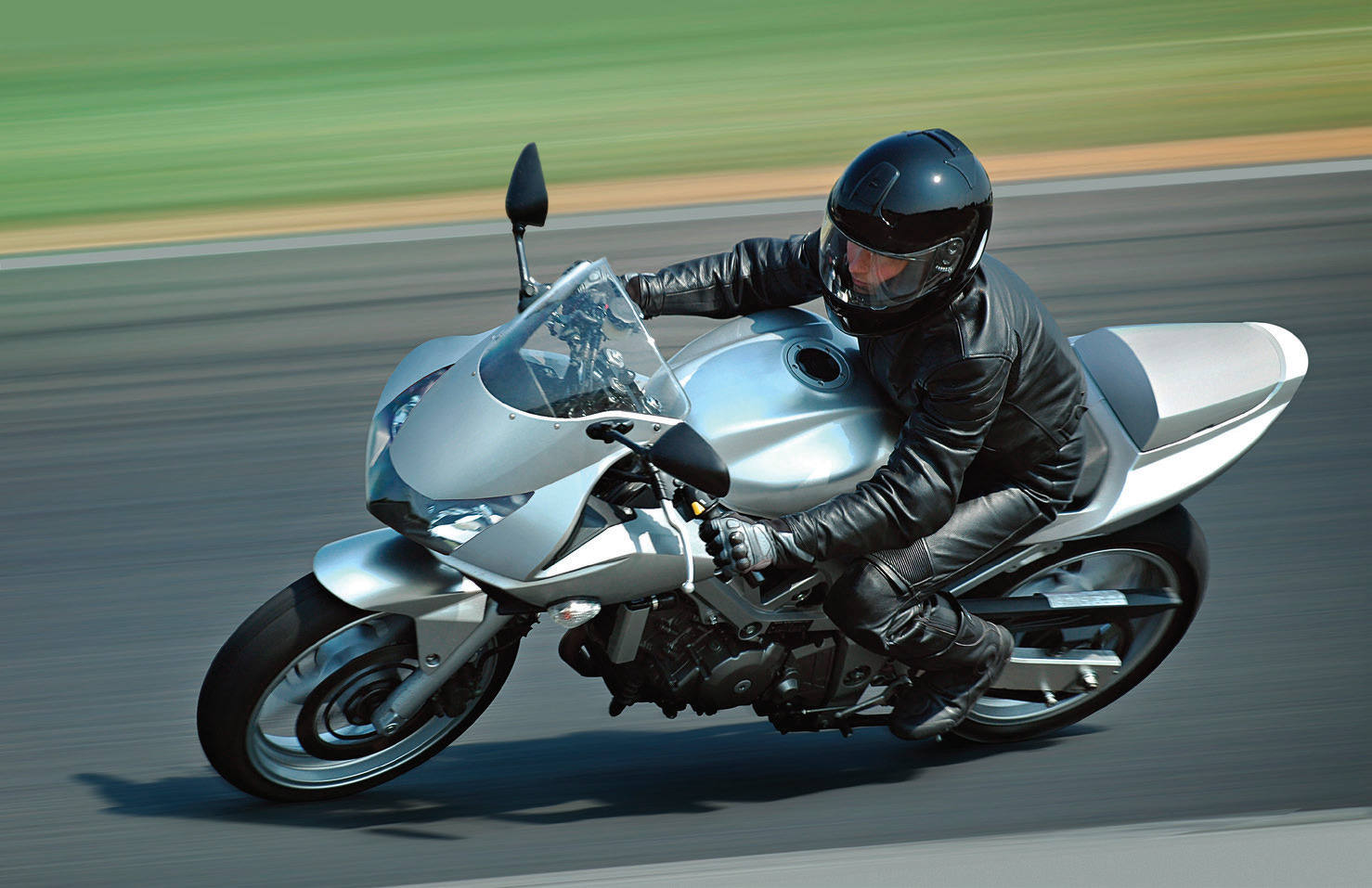  Мотоциклист на мотоцикле серебряного цвета на дороге.