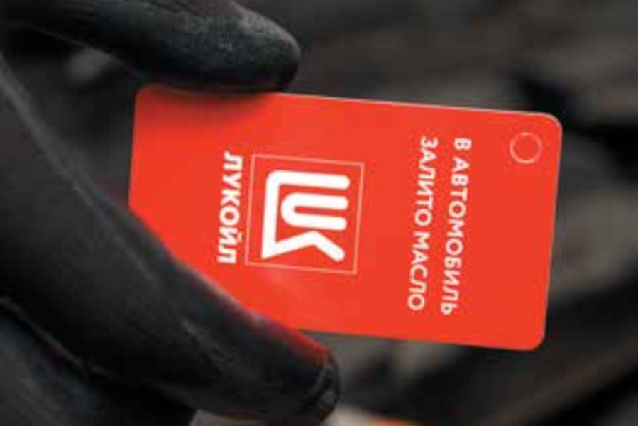 В руках мастера СТО красная табличка с текстом: В автомобиль залито масло Лукойл